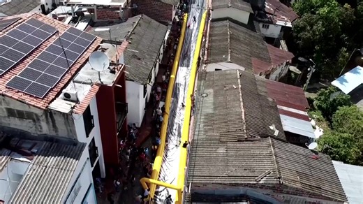 A Colombian town with a history of violent conflict and illicit activity transformed one of its main streets into a giant slide, providing a thrill for both locals and visitors. | Reuters