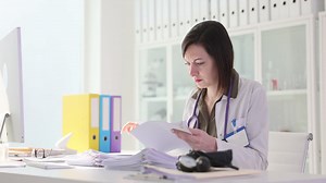 Female doctor reviewing paperwork in office | Premium Stock Video Footage