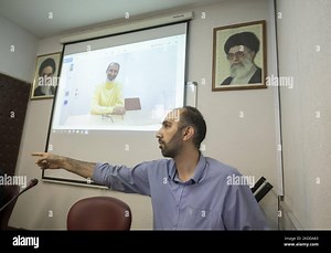 Majid Nouri, son of the former staff member of the Iranian judiciary, Hamid Nouri, points at while sitting under a portrait of Iran’s Supreme Leader Ayatollah Ali Khamenei (Top R), his father Hamid Nouri (C), and Iran’s Late Leader Ayatollah Ruhollah Khomeini during a video conference session for analyzing of the bill of Hamid Nouri’s family to the Swedish court in the Faculty of Economics of the Allameh Tabataba'i University in downtown Tehran on July 8, 2022. In November 2019, Hamid Nouri was 