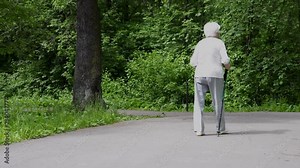 Grandma walks in the park with sticks for Nordic walking in retirement