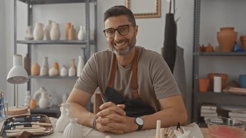 clip-3995831601-man-potter-seated-clasped-hands-on-table