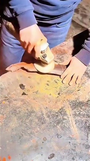 Cutting and shaping a piece of wood on a workbench, using hands to steady it while trimming edges
