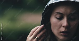 Close Up Portrait of Woman Crying in the Rain and Wind. SLOW MOTION. Sad depressed girl being emotional, crying alone, taking off raincoat hood. Stormy weather, autumn, winter, spring.