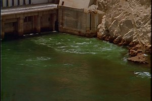 High Aswan Dam in Aswan, Egypt; Wide high angle shot of water spilling into emerald green lake from the walls of generating station.