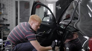 Man applying protection layer of ceraminc coating on a car with special tool.