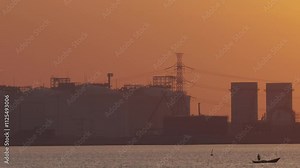 Smokestack emits smoke from power plant, silhouetted against sunset sky. This industrial skyline shows the environmental impact of fossil fuel for air pollution, carbon emissions, and climate change.