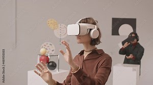 Medium slowmo shot of young woman in vr headset moving her hands during virtual reality exhibition in contemporary art museum