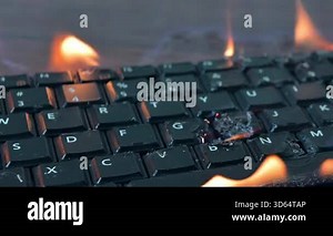 Burning keyboard. Keyboard is engulfed in flames on a desk.Close up of a burning keyboard on fire. Overheated Technology Concept