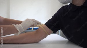 Blood sampling performed with butterfly needle and vacutainer system. Blood taken from the arm on patient with protective mask