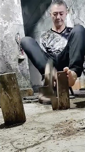 Chopping process of wood with an axe held by his foot