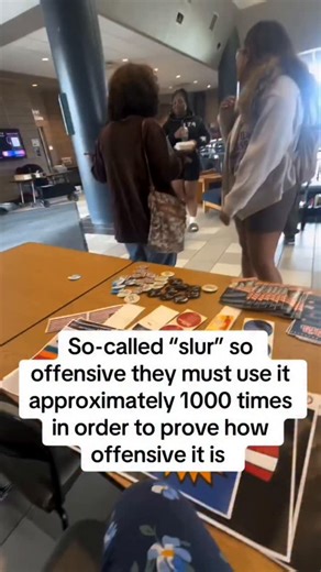 Cops Camera on Instagram: "Argument Over Racial Slur Explodes in Public—The Conversation Gets Uncomfortable Fast 😳 A heated debate breaks out in a public space when a group begins arguing over whether a commonly used word is a racial slur or personal preference. 1. The video starts with two women standing across a table filled with flyers and coins. 2. One woman clearly states that the word being discussed is a racial slur. 3. Another woman immediately challenges that claim and questions