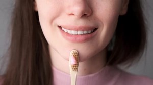 Woman Holds Toothbrush with Toothpaste Smiling