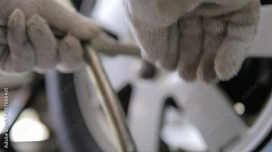 Close up shot the mechanic using cross fix wrench to spinning the bolt of a car wheel, select focus shallow depth of field