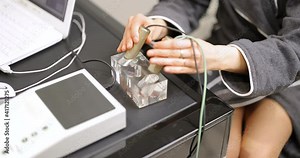 Female patient takes hold of the brass handpieces of bioenergetic testing device in medical clinic. Close-up view. Concept of bioresonance diagnosis Stock Video