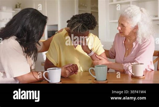 Three women sitting at home table with mugs, senior woman wiping tears, friends reaching comforting. Support, empathy, companionship, warmth, resilience, kitchen, teamwork Stock Video Footage - Alamy