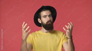 Pissed middle-eastern intense bearded man in black hat, yellow t-shirt clench fists from anger, sighing and looking outraged, wanna strangle someone standing annoyed and bothered, red background