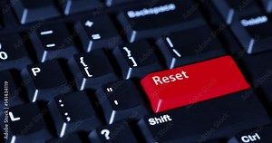 Video footage of human finger pushing a Reset button with red color on the computer keyboard