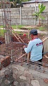 the process of installing sloof stirrups on a stone foundation.