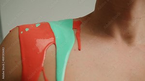 Colourful paint flowing over the man body close-up. Body art therapy with many various of paints. Painting on human body.