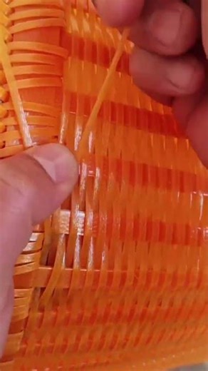 the process of assembling a basket from orange synthetic plastic neatly