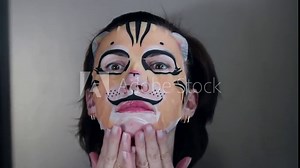 Attractive girl makes mask sheet in the form of a tiger's face. Animal mask.