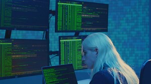 A hacker with a laptop runs code on multiple screens - Free Stock Video