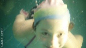 The girl in the swim hat picks up air on the surface and dives under the water. Teenage girl diving underwater. Footage above and below the water