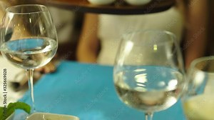 dinner service. Woman in white dress serving food drawn from wine glasses.