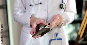 Doctor in white coat and medical gloves holds wallet with dollars in hands and takes money
