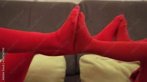 Two little girls in red tights playing in bed, pushing each other's legs