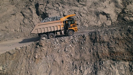 Large yellow dump truck filled with rocks driving in a quarry - Free Stock Video