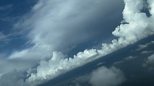 POV from the pilot’s perspective as seen from the cockpit of a real time flight through a stormy sky full of grey storm clouds and some towering white cumulus doing a right turn. 4K 60FPS