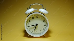 Vintage metal alarm clock on a yellow background time lapse video, ringing loudly to wake you up in the morning