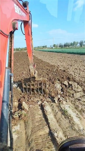 Excavator Ploughing and Turning Soil in a Field