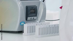 Close Up Of Medical Laboratory Specialist Taking Blood Vial For Analysis. Analysis Of Blood Vial With Modern Machine. Using High Tech Equipment For Blood Vial Analysis. Healthcare Lab