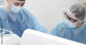 A surgeon in a medical mask sits in a bright sterile ward for an operation.