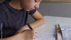 A schoolboy is learning lessons at home, a boy writing home task and schooling at home