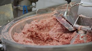 Industrial sausages production process at meat and sausage making plant. Meat processing equipment. Bowl meat chopper mixer cutter sausage making machine filled with meat for chopping.