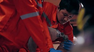 Asian man emergency medical technician (EMT) or paramedic nurse is performing CPR on a patient in an ambulance car