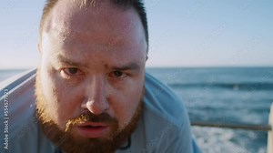 Fitness, tired man and breathing after running exercise, training or workout for recovery at the beach. Portrait of exhausted plus size male runner taking break to breath or recover from intense run