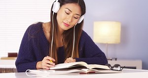 clip-6819847-chinese-woman-listening-music-while-doing-homework