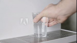 Pouring water from a water purification device into a glass. 4K