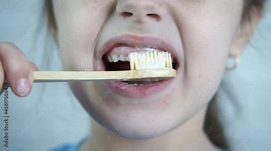A toothless child is brushing his teeth. A little girl without a tooth brushes her teeth with an eco-brush.