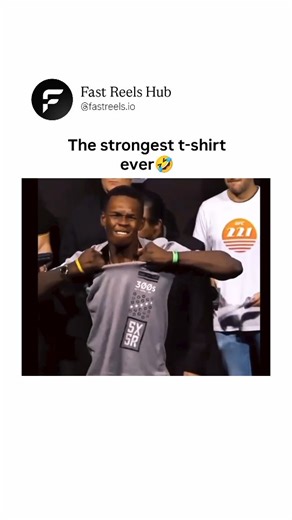 Fast Reels Hub™ on Instagram: "In a UFC weigh-in event on stage with banners reading "UFC Fight Night" and officials in suits nearby, a muscular fighter in a gray t-shirt attempts to dramatically rip off his shirt by grabbing the collar and pulling forcefully, his face contorting with effort as the fabric stretches but refuses to tear. He tugs repeatedly from different angles, yanking it over his shoulders and head in frustration, eventually removing it the old-fashioned way amid the crowd's ant