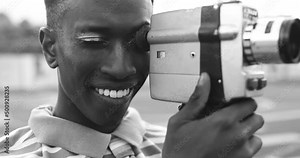 Young african man using vintage old video camera outdoor