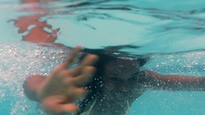 beautiful african american woman swimming underwater in pool smiling floating in blue crystal clear water having fun swim in summertime 4k