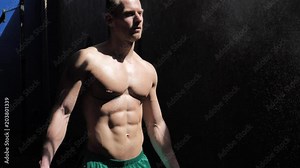 Shirtless man using chalk or magnesium powder in gym, clapping hands and creating cloud. Tattoo says Don't stop dreaming, it's still early