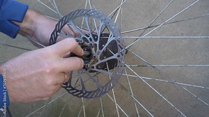 assembling a bicycle wheel hub, mountain bike repair, mechanic's hands tighten the nut on the hub of the bicycle