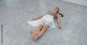 Ballerina does warm up exercises on the floor of the dance room, ballet school rehearsal, choreographer rehearses in the white dance hall, dancer in slow motion, 4k DCI 60p Prores HQ 10 bit