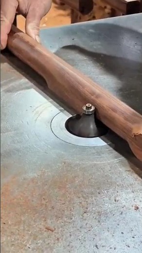 A Woodworker Using a Table-Mounted Router and Round-Over Bit to Precisely Shape a Long Timber Rail